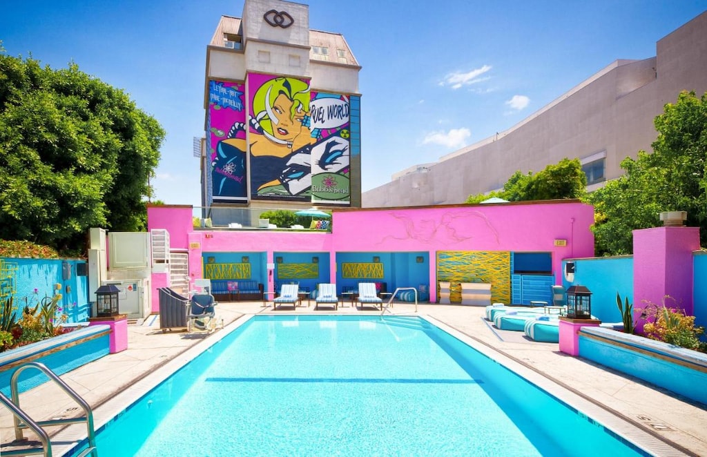colorful pink wall and mural in the distance with pool in the foreground of the best hotels in Beverly Hills CA