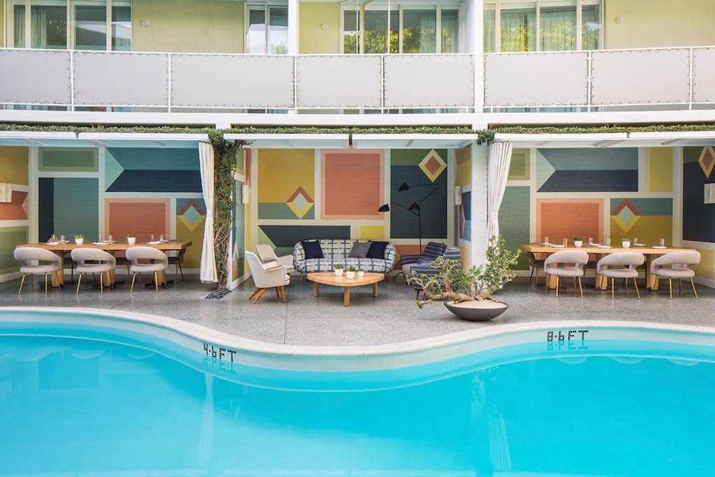 midcentury modern poolside lounge furniture with balcony and bright blue pool at cool boutique Beverly Hills hotel