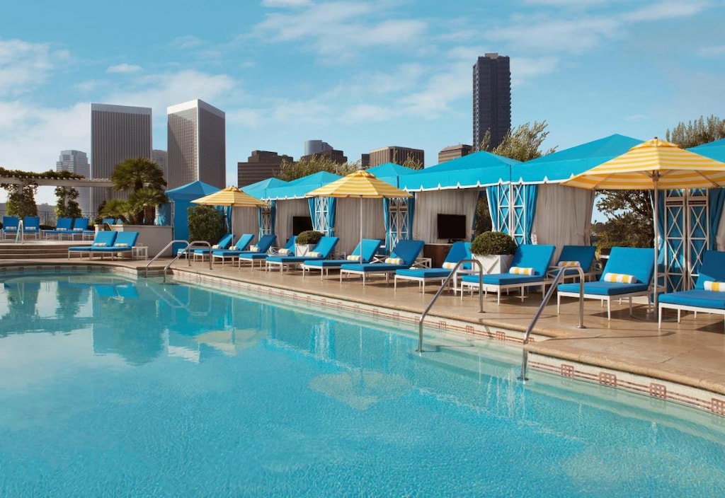 blue sun loungers with yellow umbrellas beside a pool at a cool Beverly Hills hotel