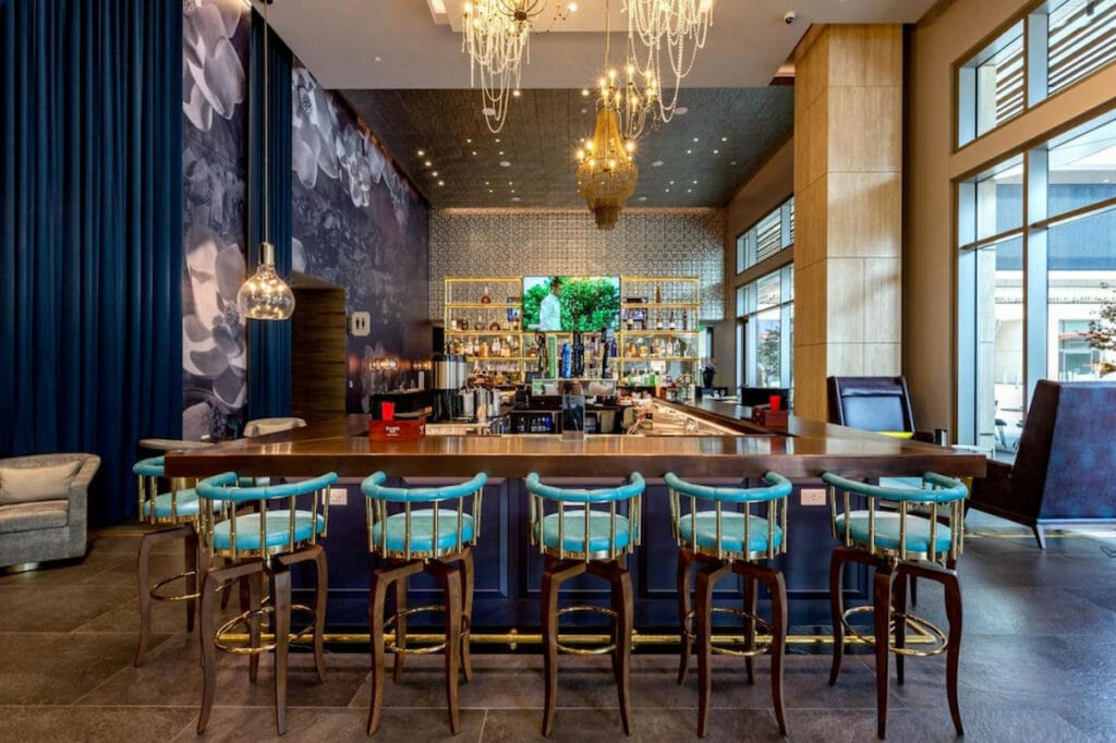 large electric colored dining hall with an expansive bar front and center with blue bar stools at one of the luxury hotels in downtown Los Angeles