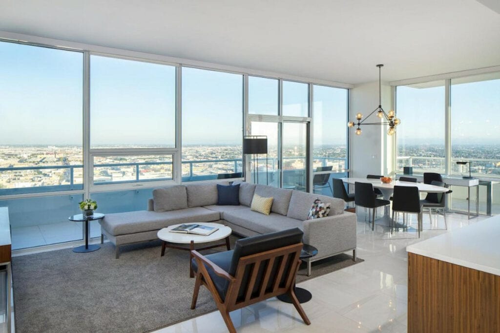 clean modern apartment in downtown Los Angeles with panoramic views of LA and a large grey sectional sofa and dining set