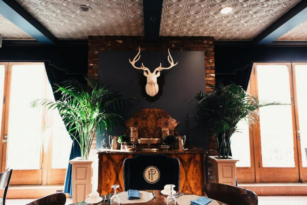 decorate white deer mounted above an ornate fireplace with black painted wall and white intricate ceiling at this luxury hotel in downtown LA