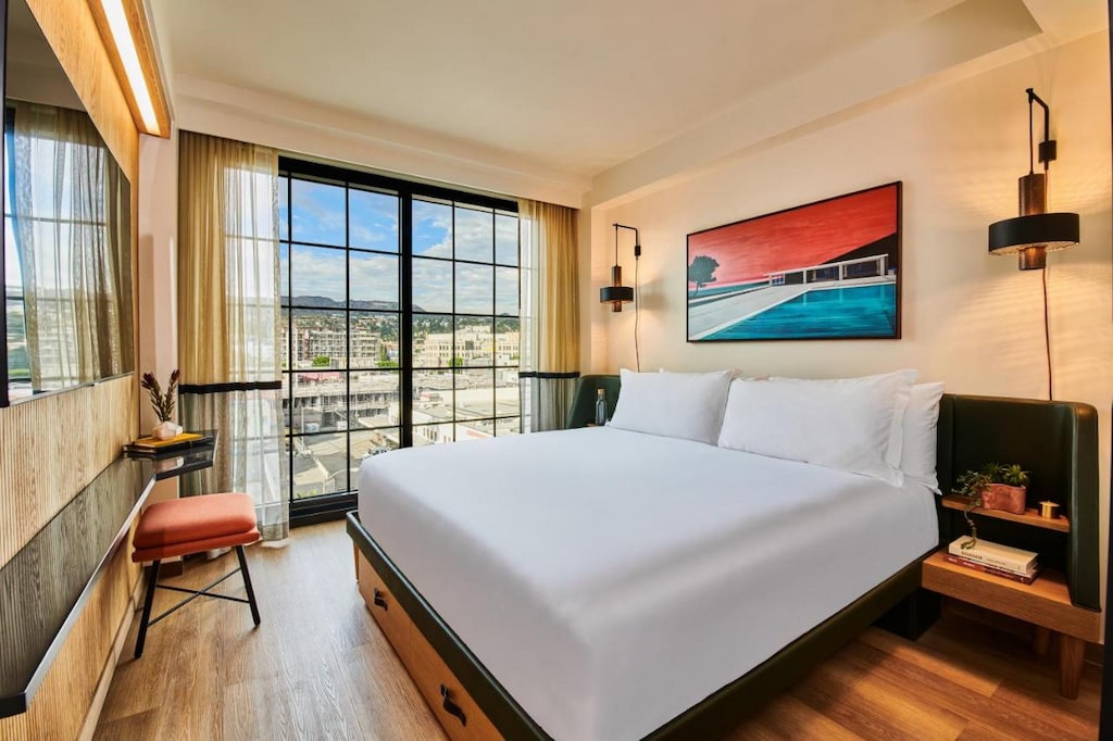 luxury hotels in Hollywood room with large king-sized bed with white linens, simple decor and window with black frame