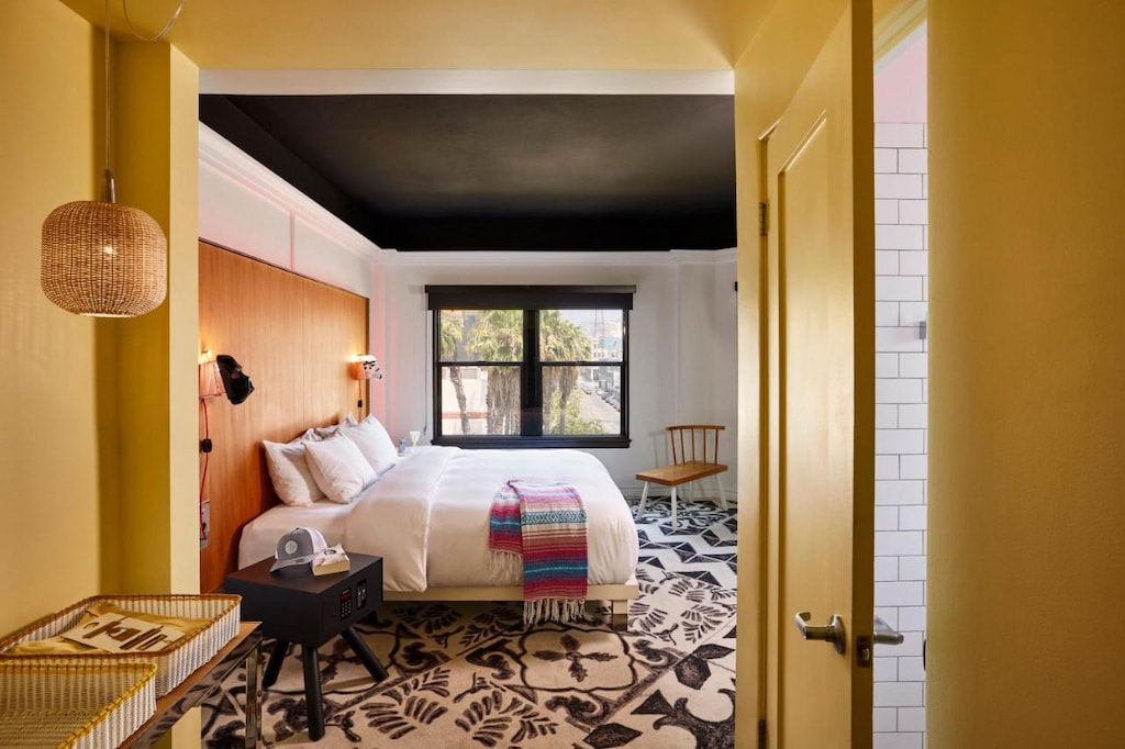 a Hollywood hotel room perspective from the entrance with yellow painted door and plush bed with black ceiling and patterned carpet