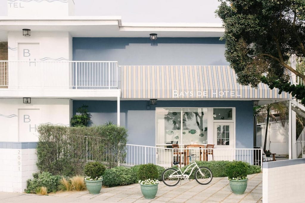 A simple cool hotel in Santa Monica's entrance with a bicycle parked outside.