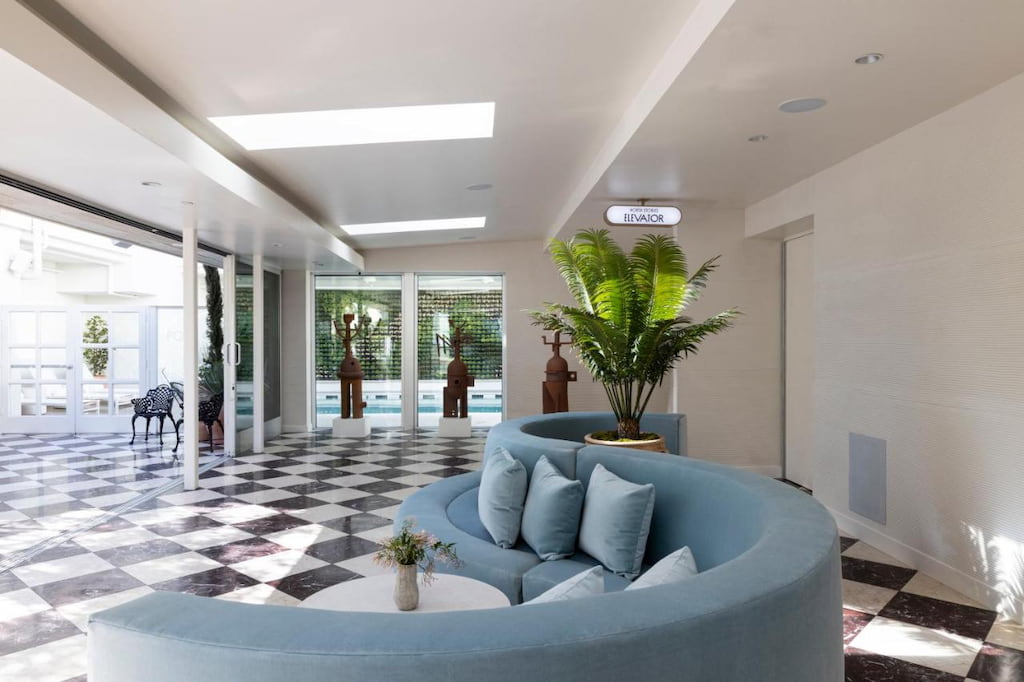 A curved light blue couch in a spacious lobby in a hotel in West Hollywood with checkered floor.