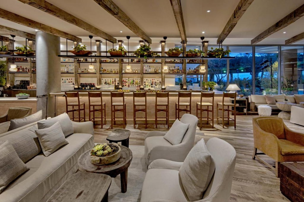 An exquisite bar area with multiple chairs and tables near the bar counter beside the shelves of bottles.