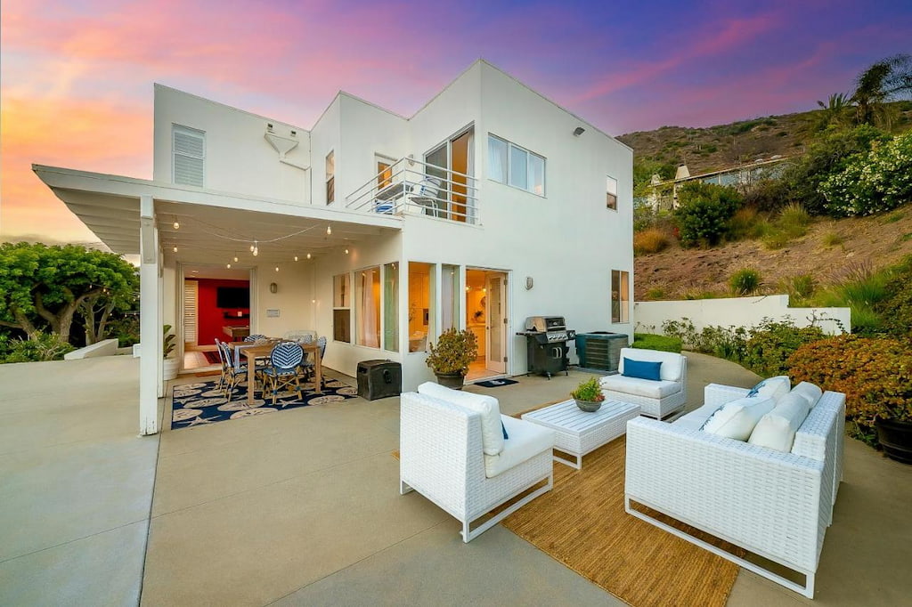 A modern style with an outdoor chairs near a white washed Malibu home rental.