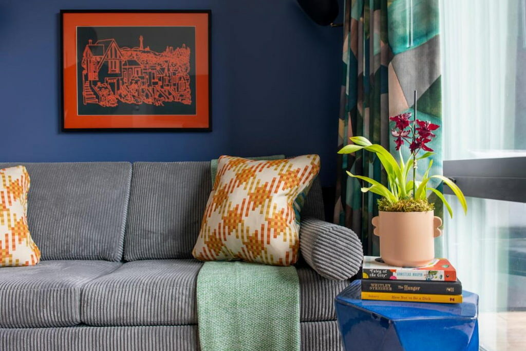 unusual San Francisco hotel living room area with gray couch beside the blue side table near the window and dark blue wall