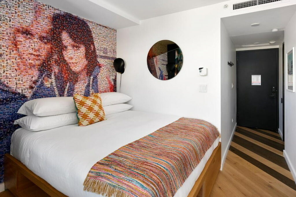 room in SF hotel with a king-size bed with white sheets below the art mural on the wall