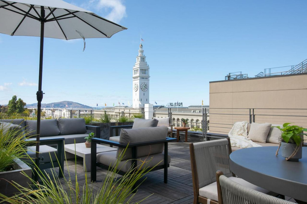 rooftop patio with panoramic views of San Francisco, low lying grey lounge furniture and umbrella