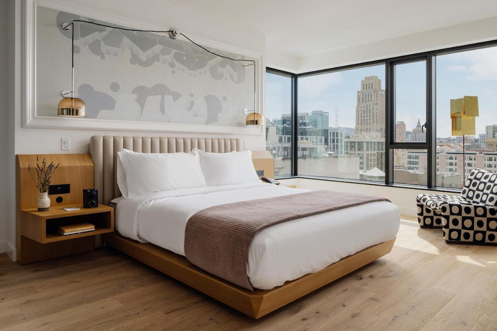 View from one of the best boutique hotels in Union Square San Francisco with a cozy bed with white sheet near the black and white accent chair in the corner of the room
