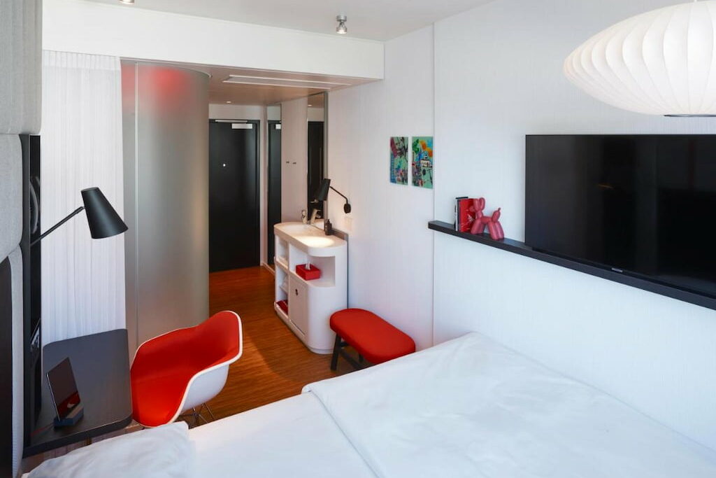 one of the hotels in Union Square SF with all-white room with a red accent chair beside the bed