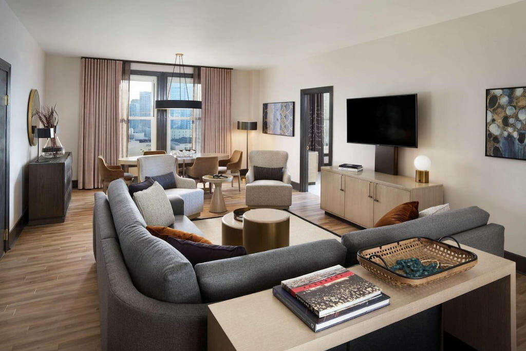 hotel suite area with grey couch in front of the flat screen TV above the console cabinet
