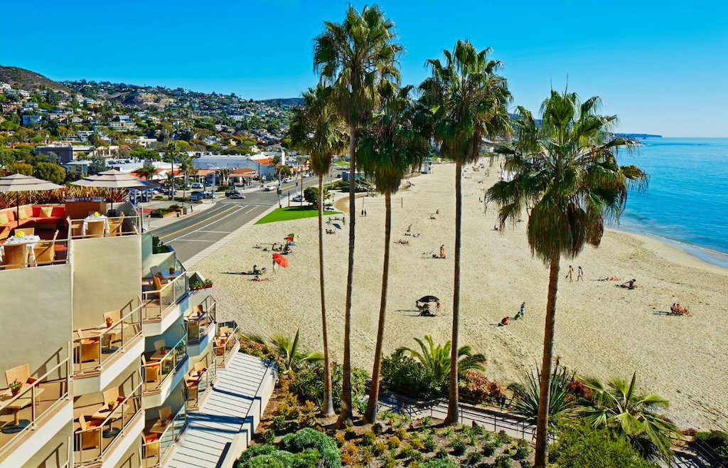 Laguna's Main Beach stretches along the coastline with some of the best boutique hotels in Laguna Beach on the shorefront on a sunny blue day
