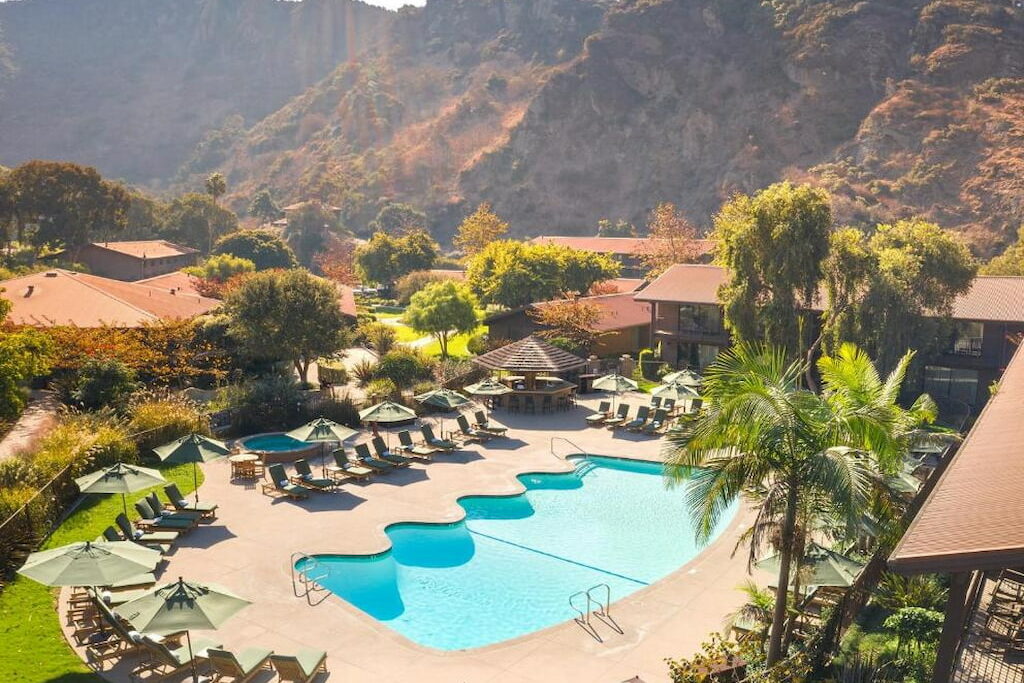 aerial view of an outdoor hotel pool area surrounded by trees and mountains