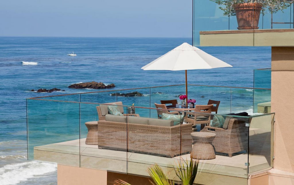 terrace with transparent railings, white umbrella and low furnishings and an amazing view of the beach