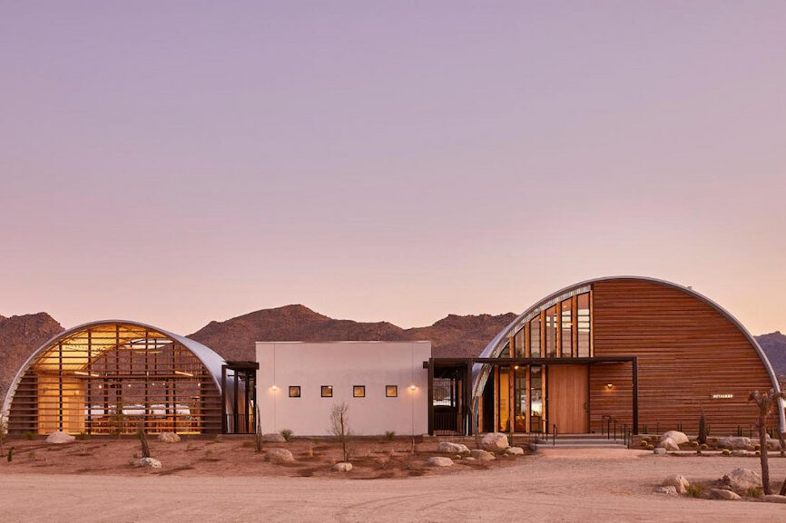 Joshua Tree boutique hotel with unique curved roof in the desert under a pink dawn sky
