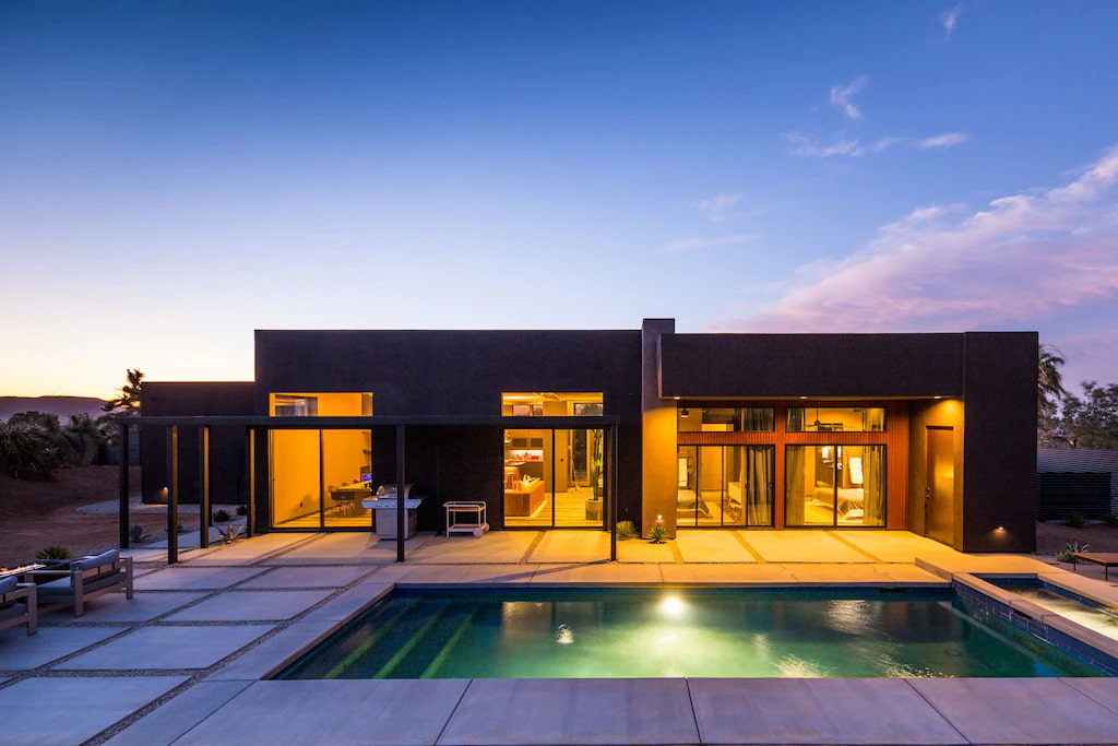 boutique hotels in Joshua Tree with a lit up outdoor pool and floor-to-ceiling windows at twilight