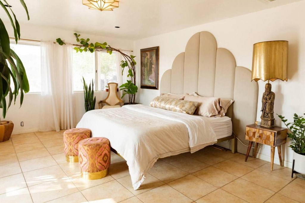 bedroom with a king-size bed with white blanket and two orange stool chairs at the bottom