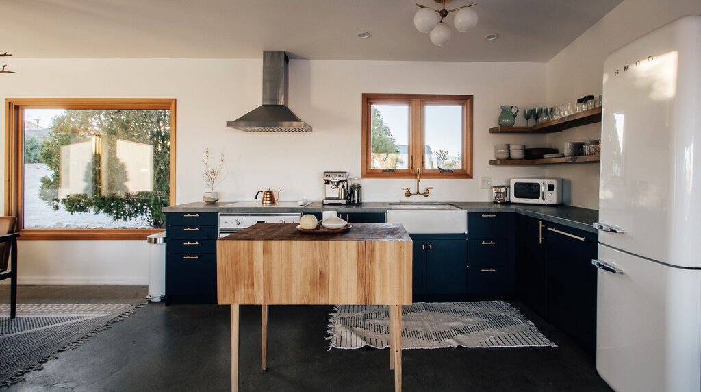 modern kitchen with central wood butcher block island and black cabinets in a Joshua Tree house rental