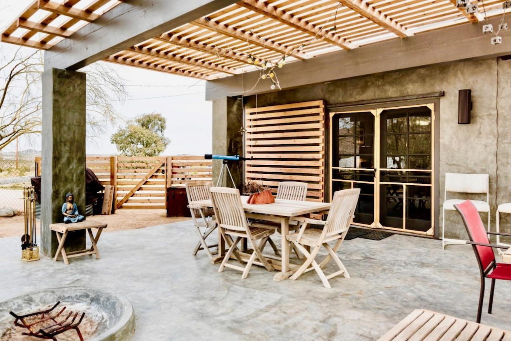 an outdoor dining area with wooden tables and chairs near the fire pit