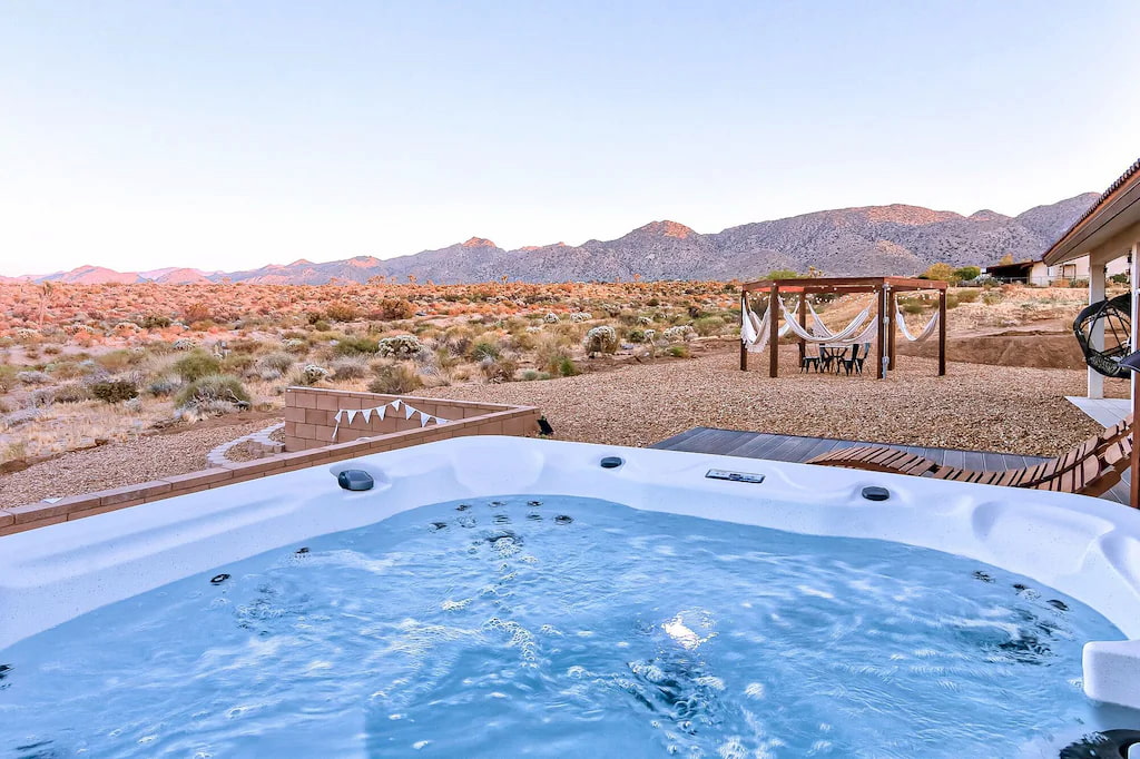 whirling jacuzzi in the foreground of a Joshua Tree rental backyard with colorful view of the desert at sunset