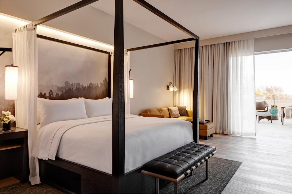 best Napa boutique hotels with a luxurious bed with a black frame and a black bench below it.