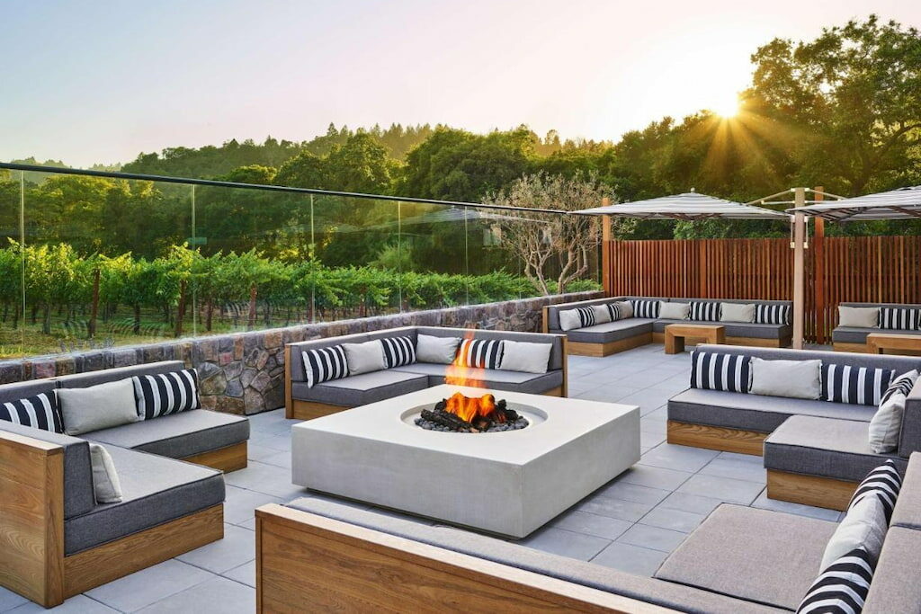 A modern fireplace surrounded by outdoor sofas as the sunsets.