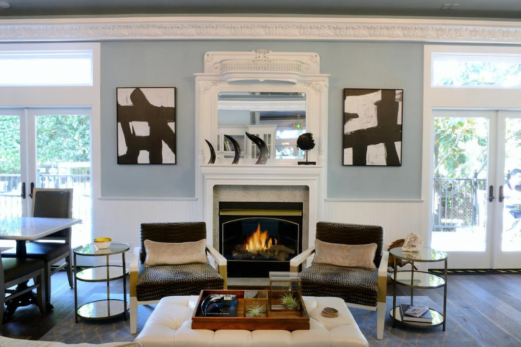 modern style living room with accent chairs with animal skin cover near the fireplace below the mirror