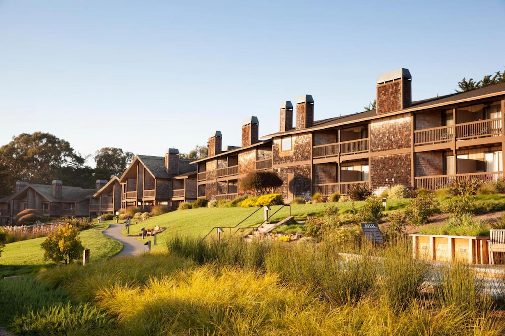 Exterior panoramic of a boutique hotel along the Northern California surrounded by green landscape and trees under a clear sky