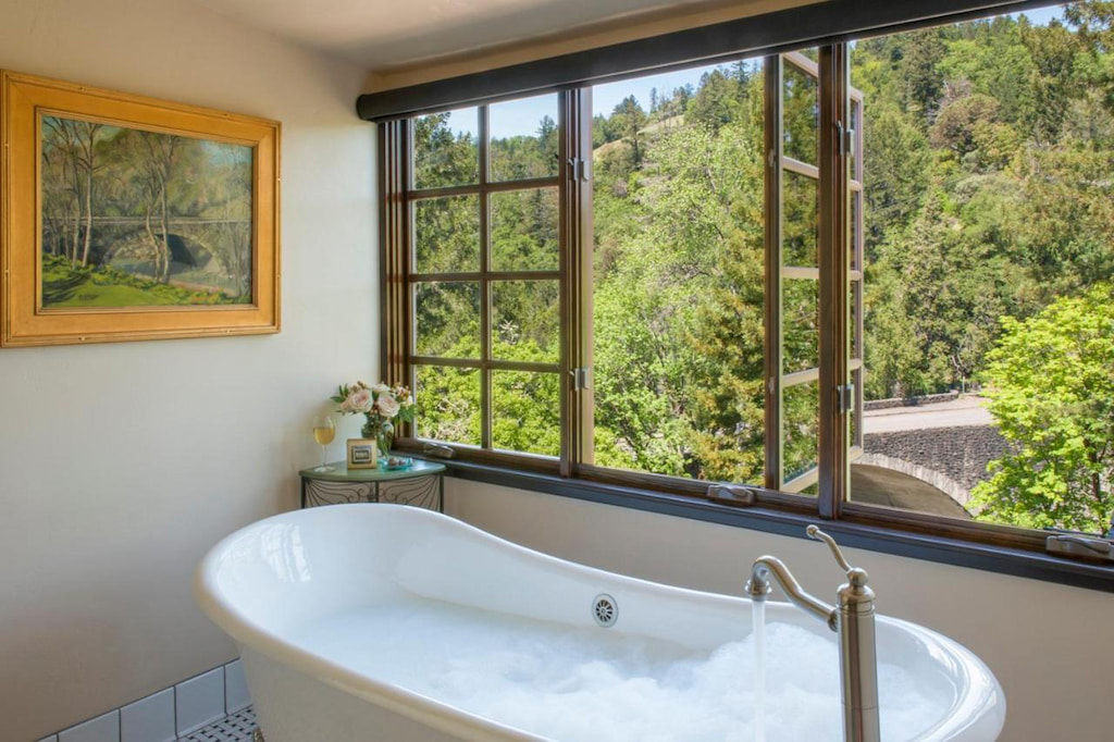 bathroom area with a white clawfoot tub beside the window and view of the forest