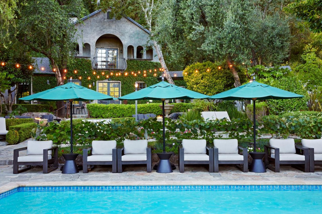Cozy chairs beside green umbrellas surrounded by green plants and trees in one of the best hotels in Northern California.