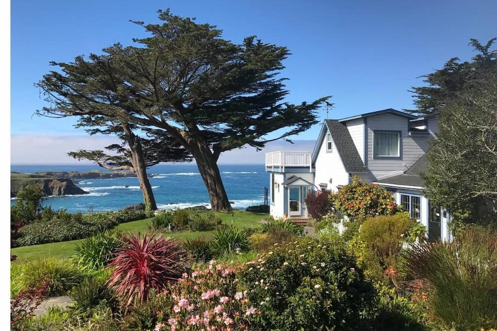 small historic boutique hotel in Northern California with a variety of greenery and foliate along the coastline on a sunny day with large tree