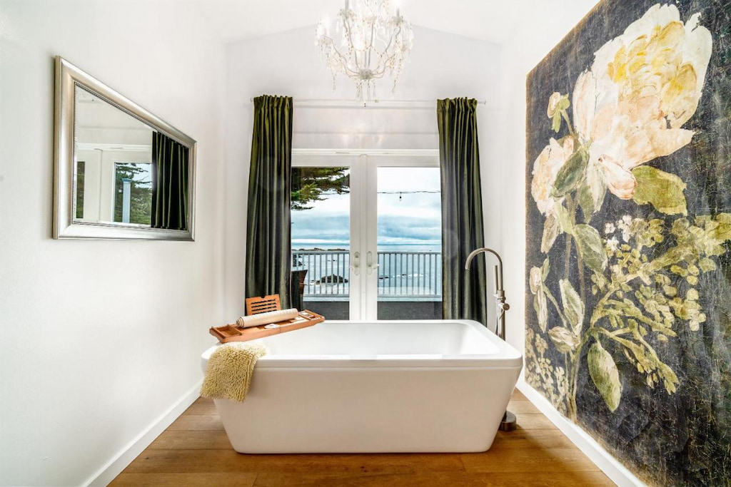 bathroom area with a modern white bathtub and view of the ocean from its window