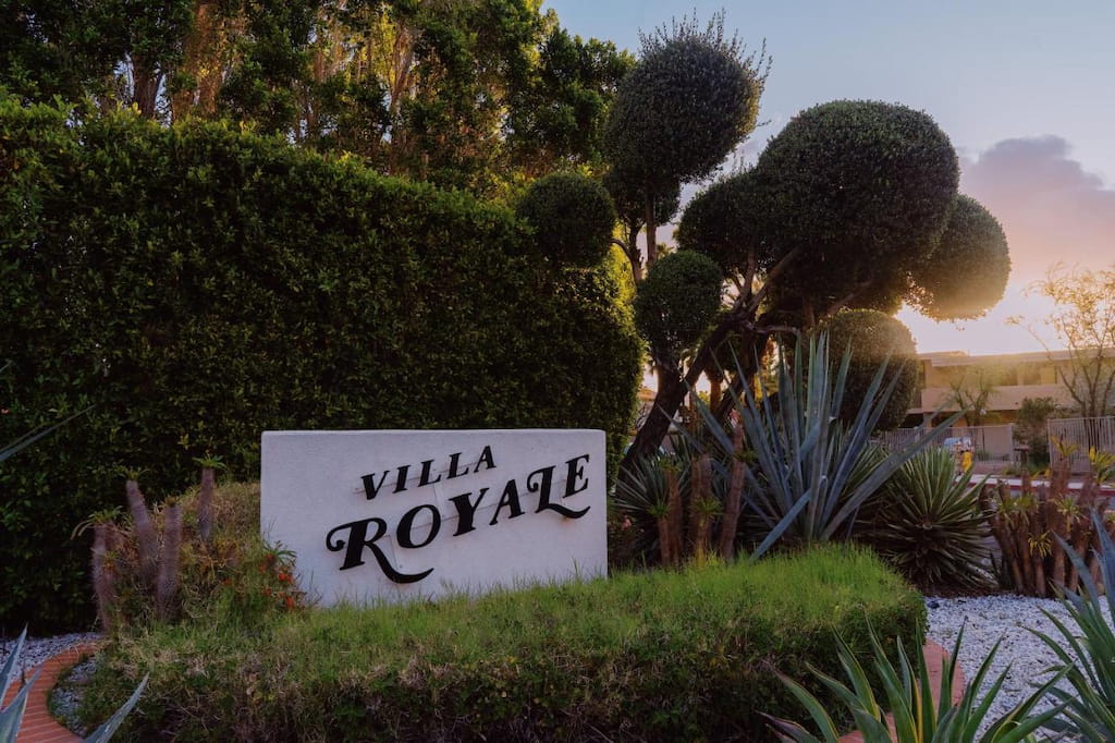 View of the signage of Villa Royale surrounded by trees and bush.