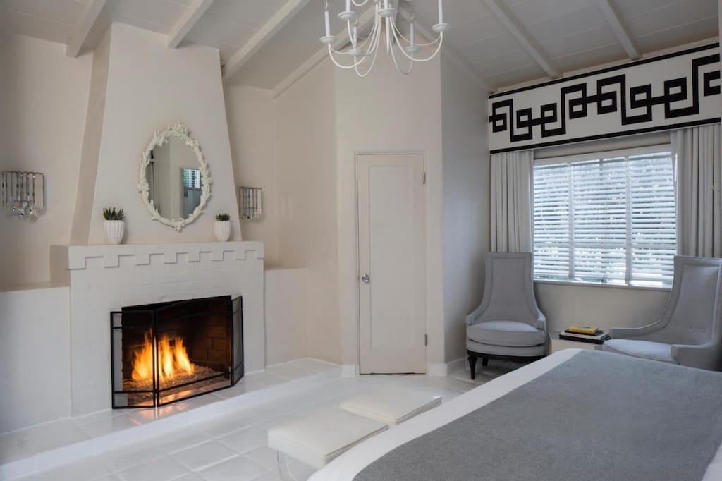 A modern style hotel with a fireplace in an all white room.