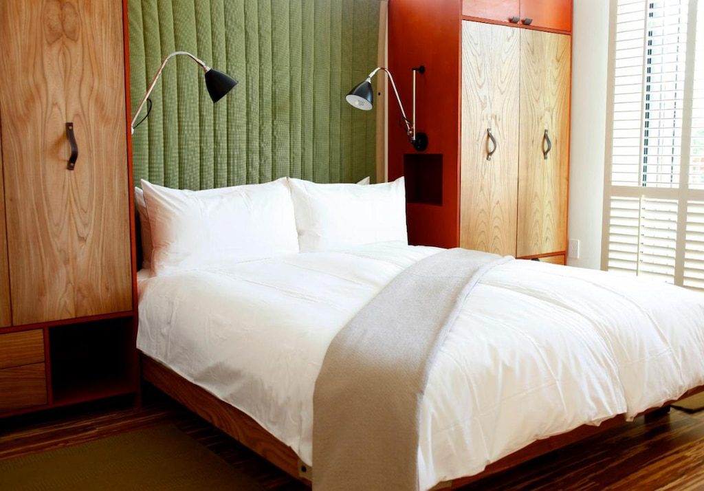 bed beside wooden wardrobes and plush green feature wall