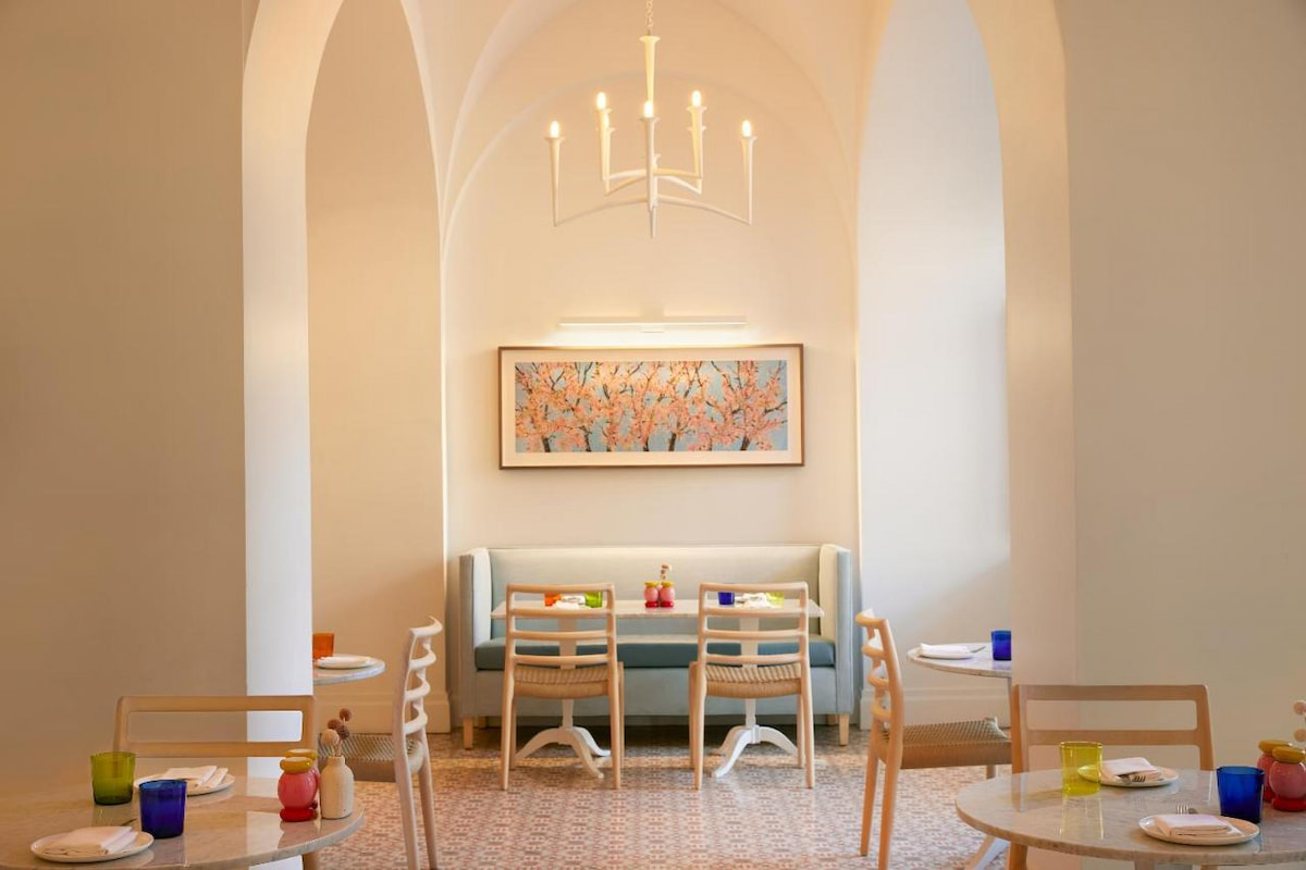 A simple dining area in one of the best hotels in Southern California for families with tables, couch, chairs, framed art, chandelier, and colorful cups