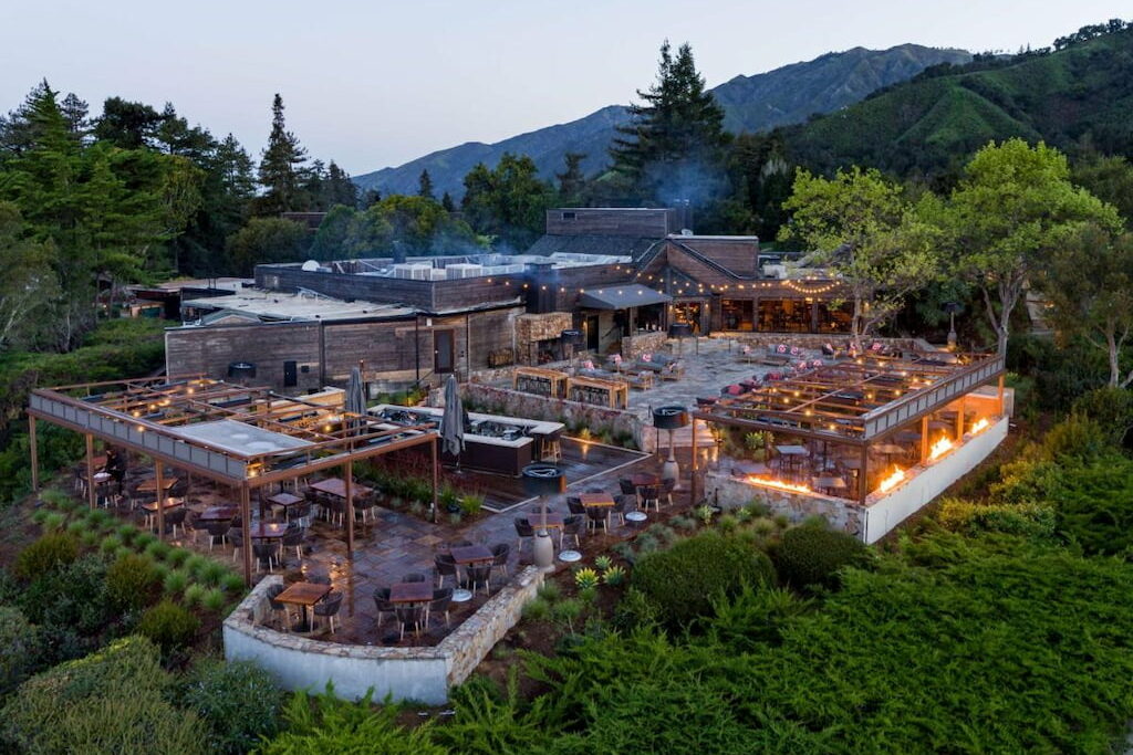 Panoramic of a multi level adults only Big Sur resort at dusk with forest and mountains.