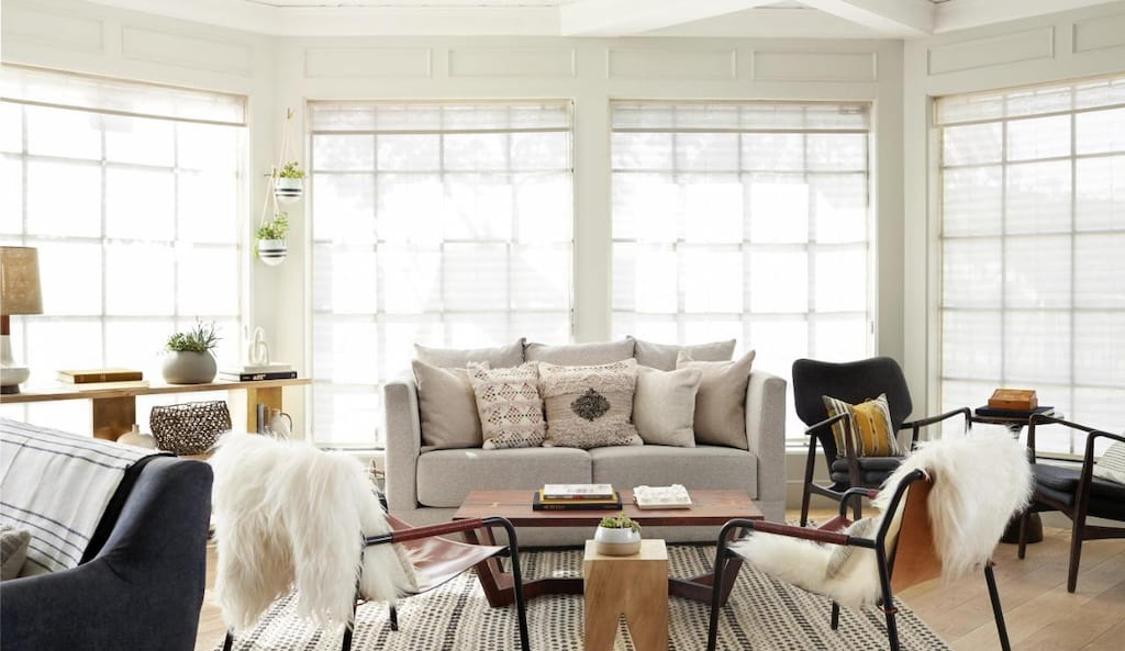 A living room with a gray sofa and a couple of accent chairs facing the windows.