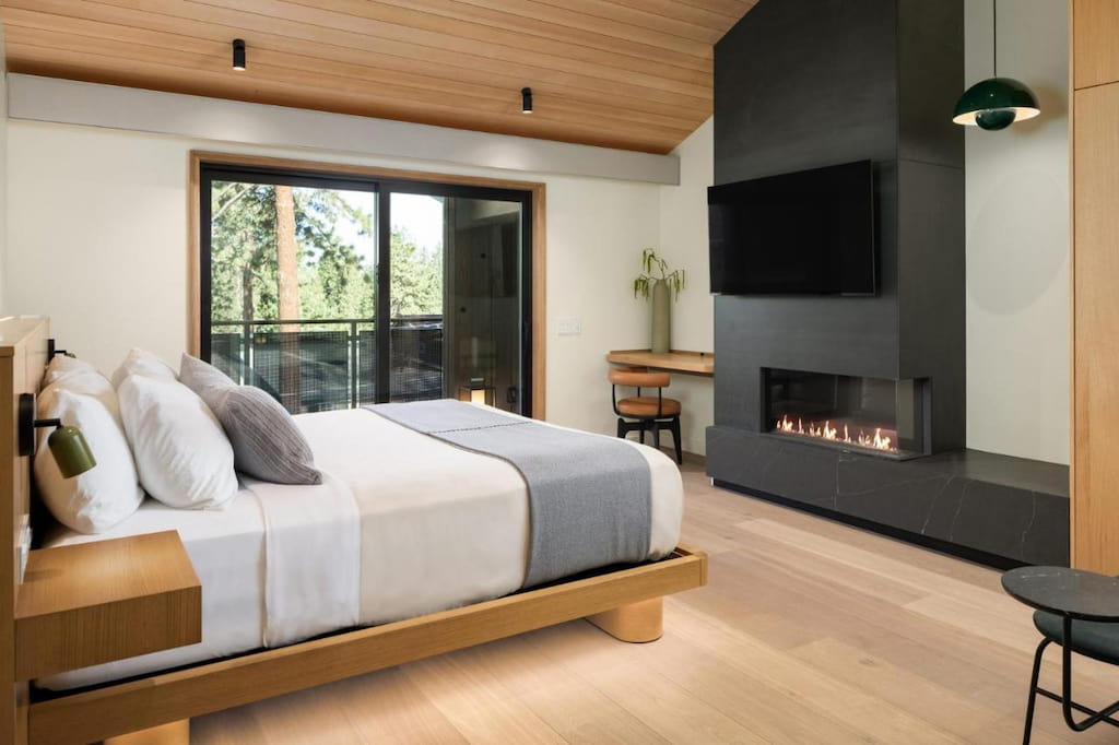 a modern room in a hotel in California with a bed and a modern fireplace below the flat screen TV.