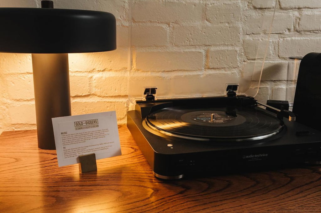 a vinyl record player beside the lamp on a wooden table in a cool hotel in California.