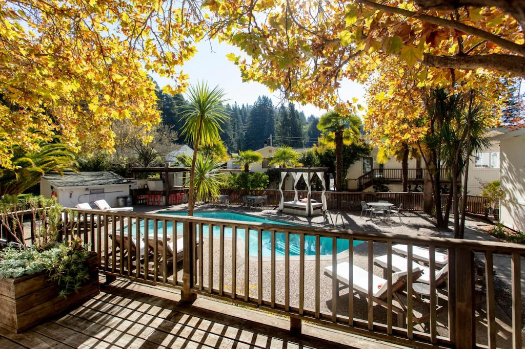 perspective of a boutique Russian River resort in Guerneville California with a pool,  wood railing and lush yellow trees