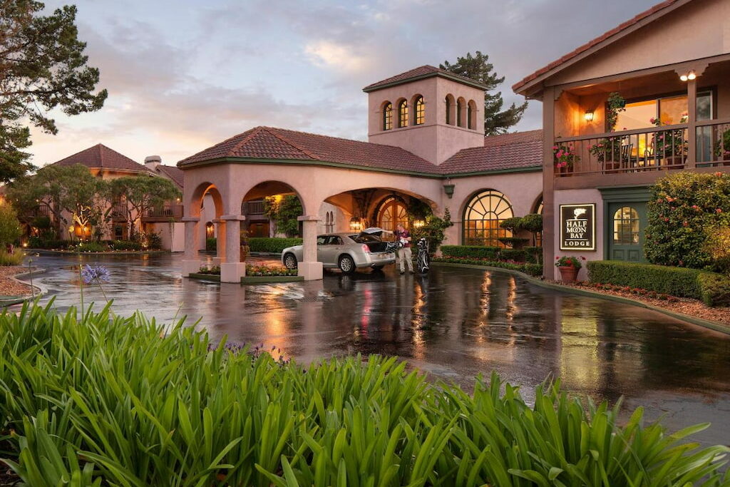 Entrance of one of the hotels at Half Moon Bay with a parking valet on a wet roadway.