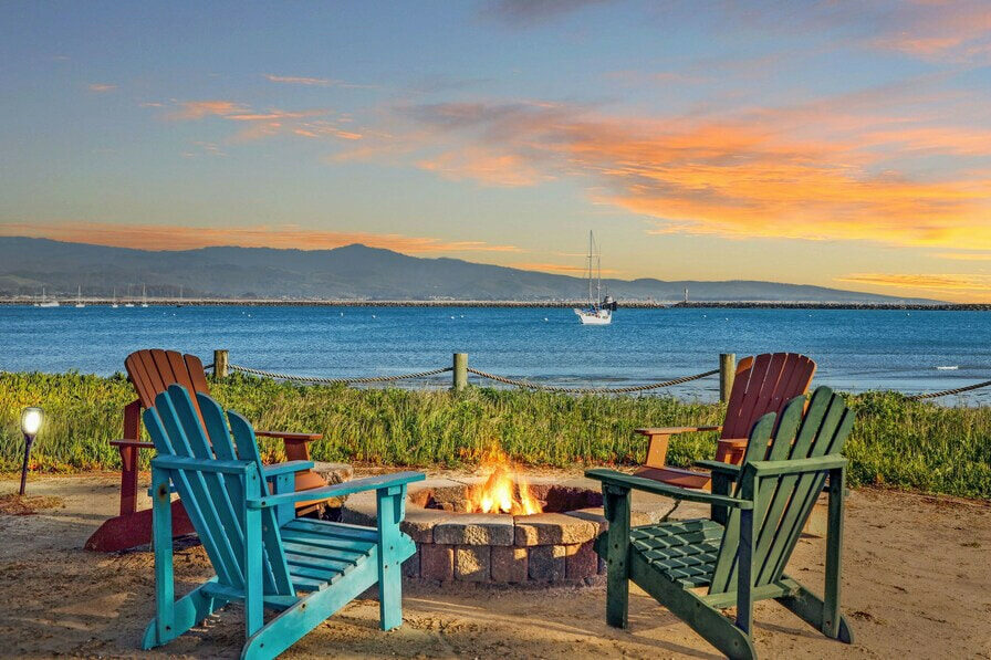 A sitting area outside the property with a fire pit and beautiful view of the beach.