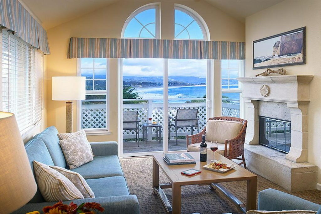 Half Moon Bay hotel suite with a cozy sofa set , fireplace and a wooden center table near the balcony and view of the beach.