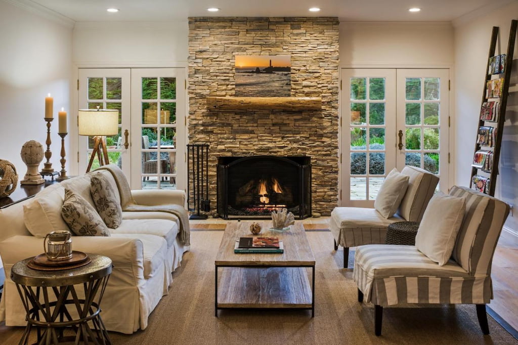 A beach house at Half Moon Bay with a spacious living room with cozy sofa set, a center table and a fireplace with two glass doors.