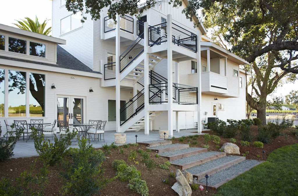 three story luxury hotel in Paso Robles with all white villa exterior, stone steps and manicured garden with large trees