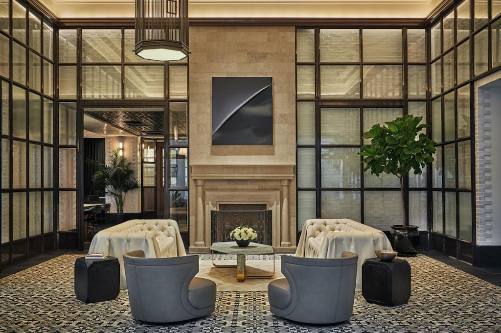 sophisticated lobby in a boutique San Diego hotel with tall beige marble fireplace, and grey lounge chairs
